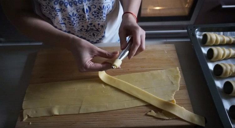 Avvolgiamo ogni striscia di pasta su una forma di tubo.