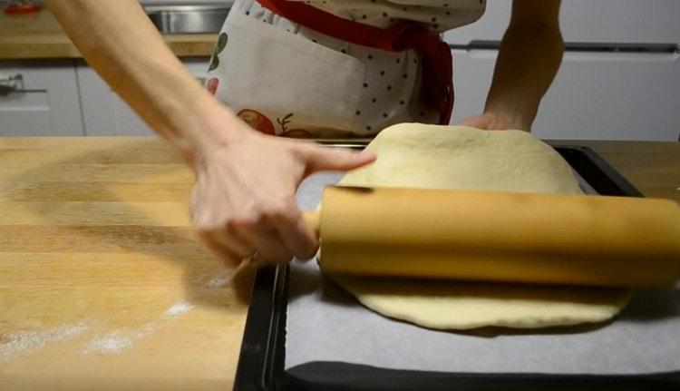 Usando un mattarello, trasferisci il khachapuri su una teglia.