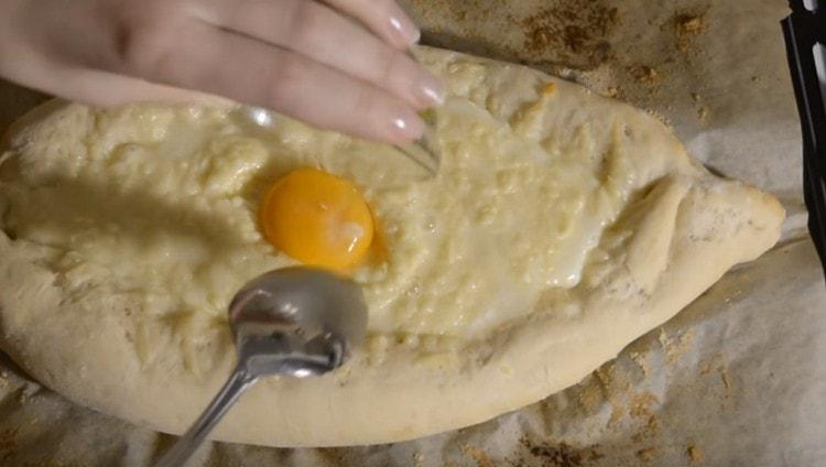 Nel mezzo del processo di cottura di un tale khachapuri, battiamo l'uovo al centro del ripieno.