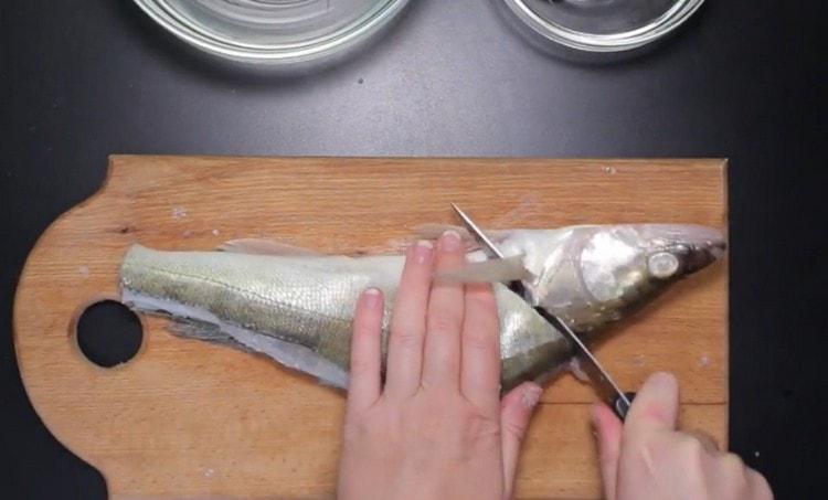 Senza tagliare fino alla fine, separiamo la testa del pesce dal corpo.