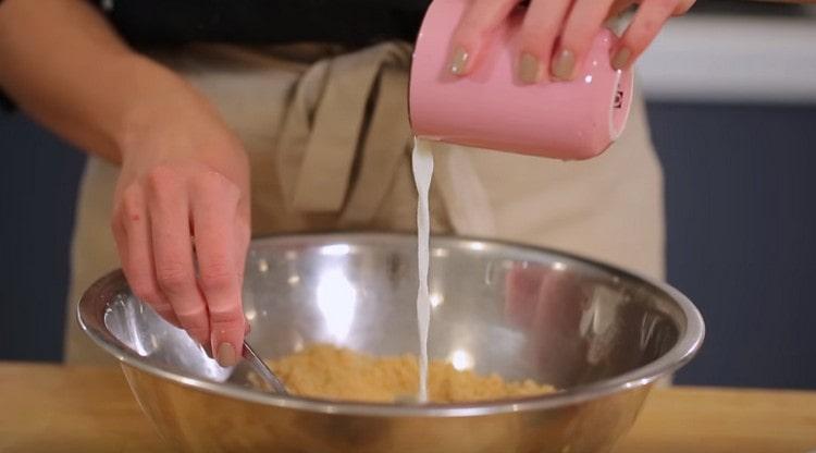 Aggiungi il latte alle briciole di biscotti e impasta questa massa.