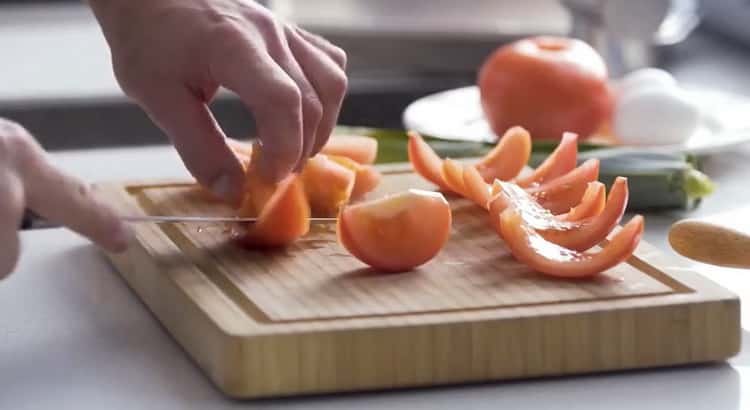 Per cucinare la quiche con il pesce, tritare i pomodori