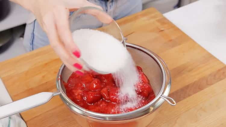 Per preparare la cheesecake alla fragola, mescola le bacche con lo zucchero.