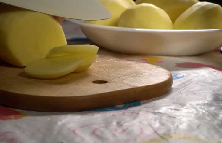 Per preparare il merluzzo con le patate al forno, tritare le patate