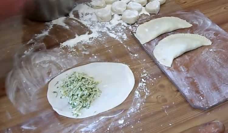 Per fare le chebureks con il formaggio, metti il ​​ripieno sull'impasto