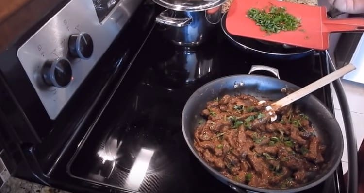 Lo stroganoff di manzo pronto dal fegato di manzo con panna acida può essere cosparso di erbe tritate.