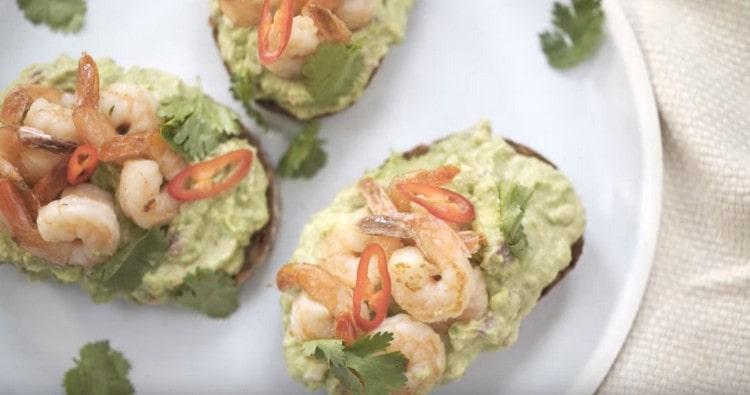 Una tale bruschetta con avocado e gamberi sarebbe appropriata anche sul tavolo festivo.