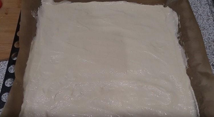 L'impasto per pizza a base di kefir è distribuito uniformemente su una teglia coperta di pergamena.