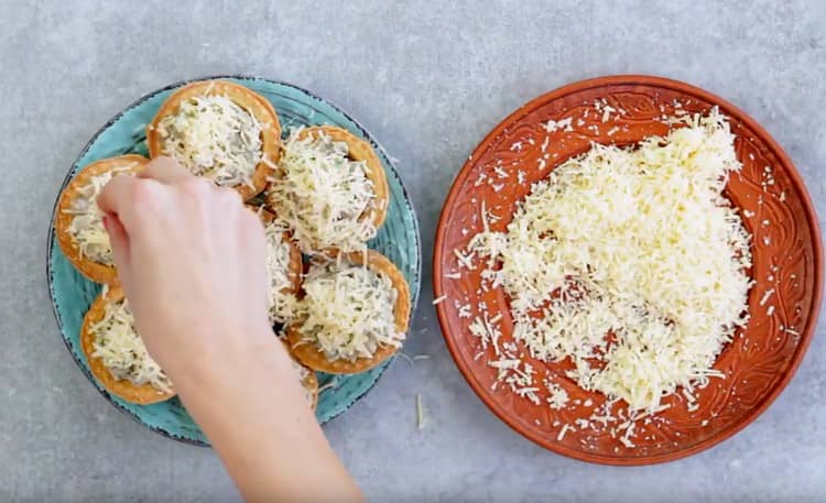 Cospargere le tortine ripiene di formaggio grattugiato.