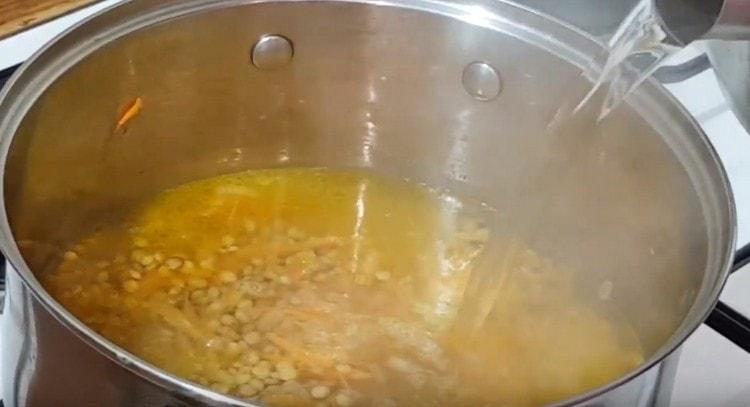 Mettiamo le lenticchie nella padella e versiamo tutto con acqua bollente.