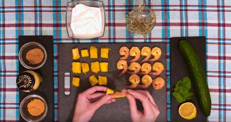 Su uno spiedino infiliamo dei gamberi, una foglia di menta e una fetta di mango.