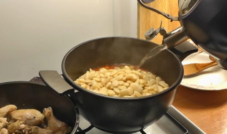 Trasferiamo i fagioli bolliti in salsa di pomodoro, aggiungiamo acqua.