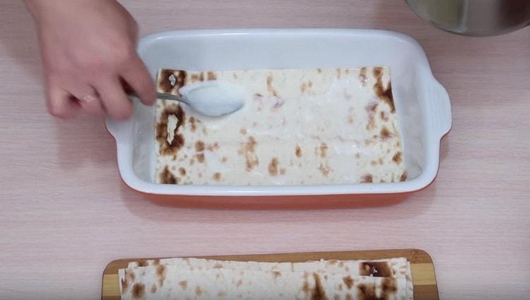 Distribuiamo il foglio di pane pita, ungere con la salsa di latte.