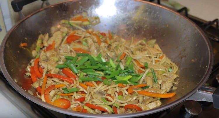 Mescolare udon con pollo e verdure, aggiungere cipolle verdi.