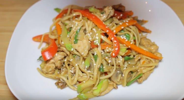 Le tagliatelle di Udon con pollo e verdure appariranno ancora più appetitose se cosparse di semi di sesamo durante il servizio.