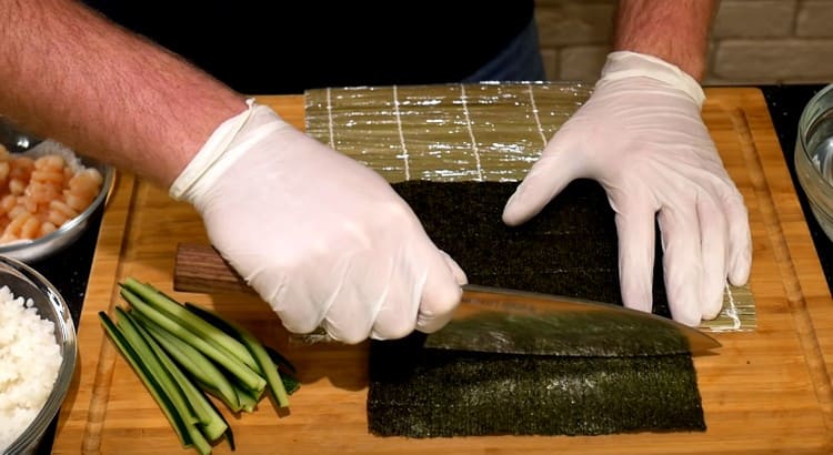 Distribuiamo il foglio di nori sul tappetino, tagliamo il bordo in eccesso.