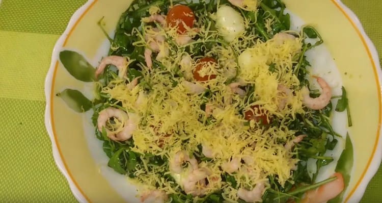 Insalata pronta con rucola, gamberi e pomodorini cospargere con formaggio grattugiato.