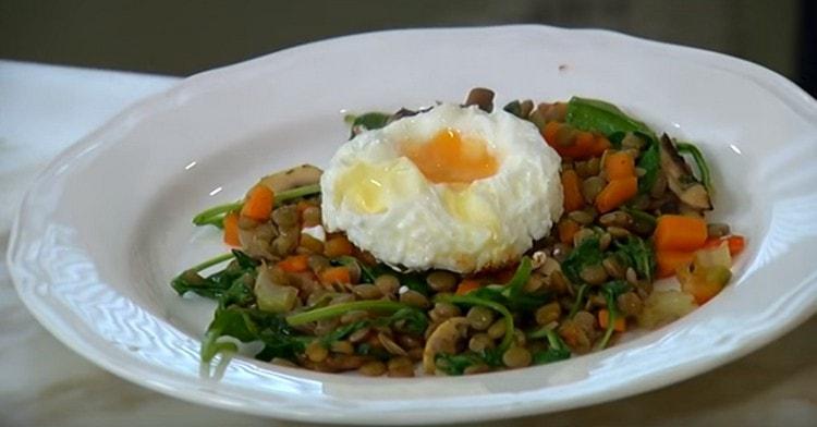 Metti l'insalata con le lenticchie su un piatto da portata e decorala con un uovo sopra.