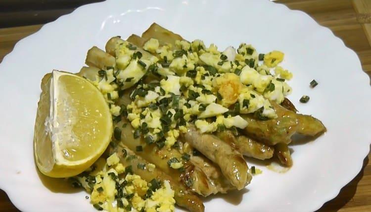 Asparagi bianchi serviti con uova e cipolle verdi.