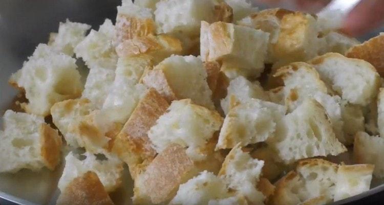 Taglia il pane bianco a dadini e spalmalo in una padella.