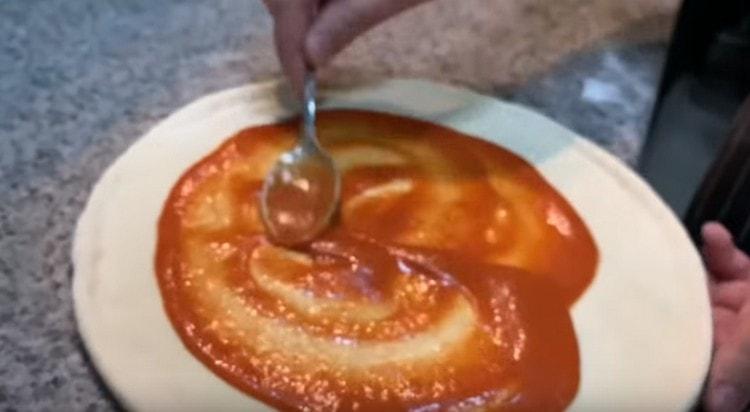 Se vuoi cucinare la pizza Margarita, ingrassa la base dell'impasto con la salsa di pomodoro.