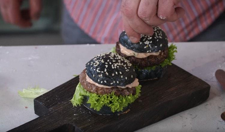 Mettiamo ancora un po 'di salsa sulla cotoletta, copriamo il tutto con un panino e il nostro hamburger nero è pronto.