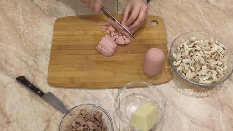 Per cucinare la julienne in tortine, tagliare la salsiccia