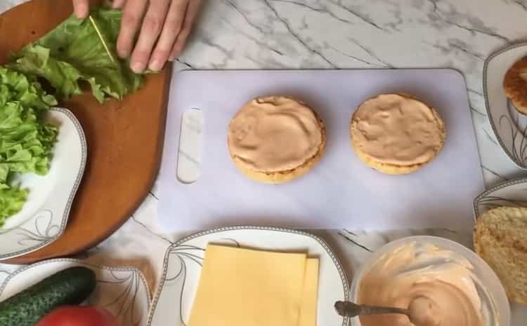 Per preparare un chickenburger, metti la salsa su un panino