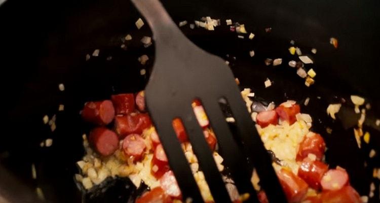 Tagliare a pezzi di salsiccia e aggiungere alla cipolla.