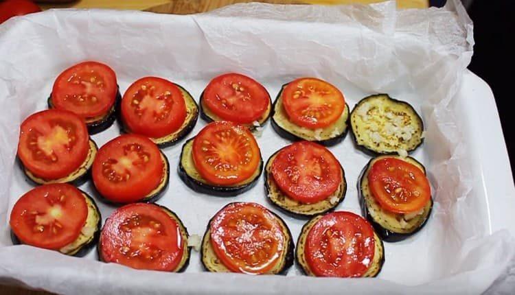 In cima a ciascuno con fette di melanzane, stendi un cerchio di pomodoro.