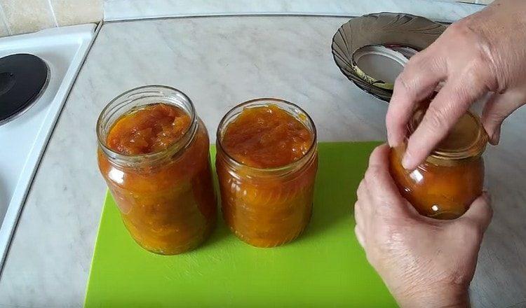 Posiamo la marmellata di zucca con albicocche secche in barattoli sterilizzati e torchiamo le palpebre.