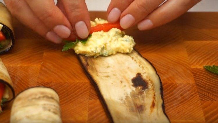 Su una fetta di melanzane fritte, metti un po 'di ripieno, una foglia di prezzemolo e una fetta di pomodoro.