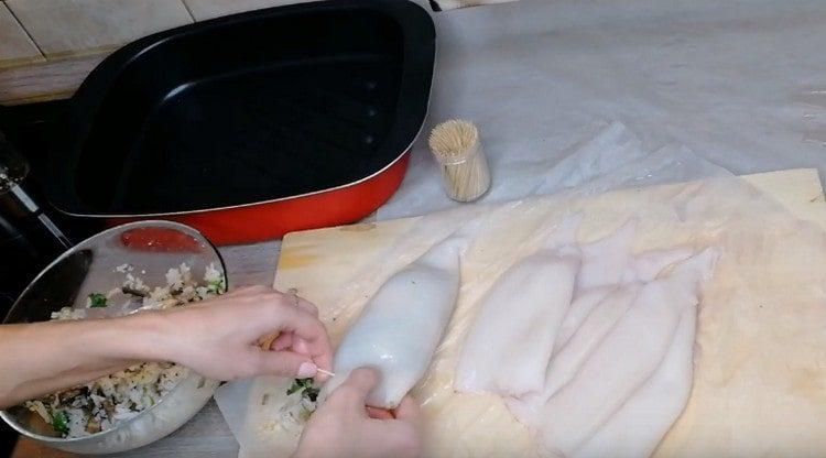 Iniziamo le carcasse di calamari, fissiamo i bordi con stuzzicadenti.