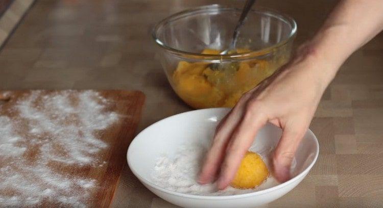 Dalla massa di zucca formiamo delle palline e le arrotoliamo nella farina.