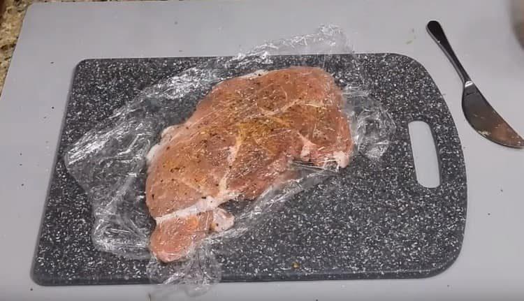 Pezzi di carne sono disposti uno sopra l'altro, avvolti in una pellicola e lasciati marinare.