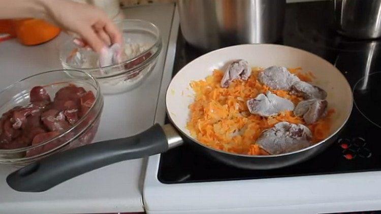 Pezzi di fegato rotolano nella farina e si diffondono in una padella per le verdure.