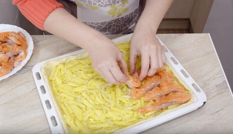 Mettiamo patate con cipolle sull'impasto e pesce in cima.