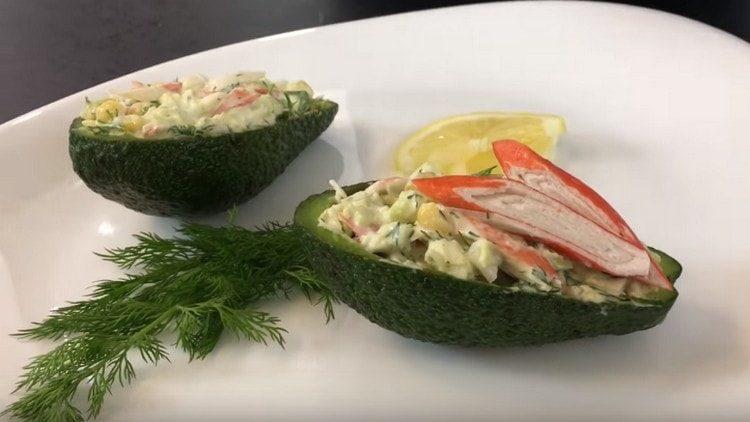 Serviamo un'insalata con avocado e bastoncini di granchio in bucce di avocado.