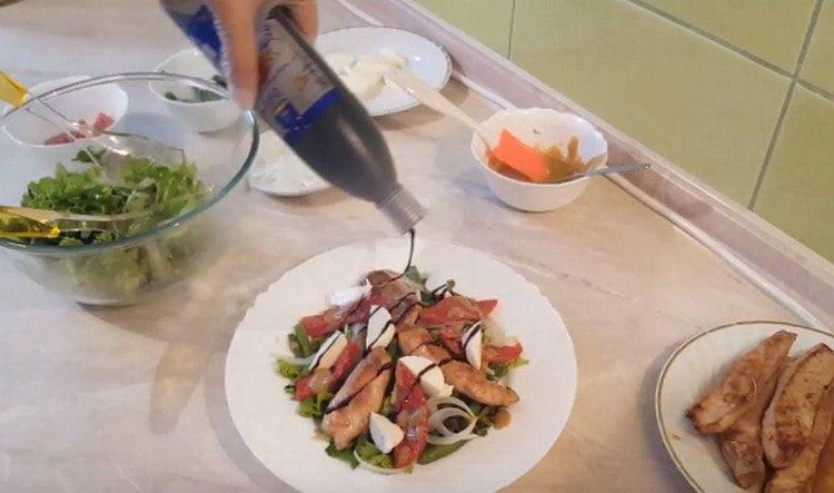 Decoriamo l'insalata con pomodori secchi con fette di mozzarella e versiamo sopra la crema balsamica.