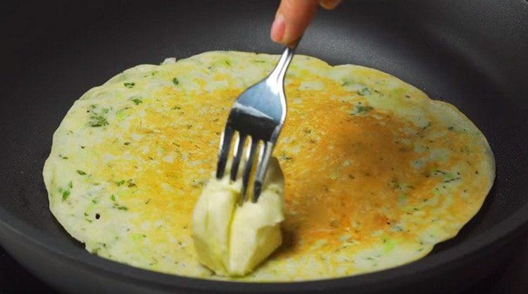 Girare il pancake dall'altra parte e lubrificare immediatamente con un pezzo di burro.