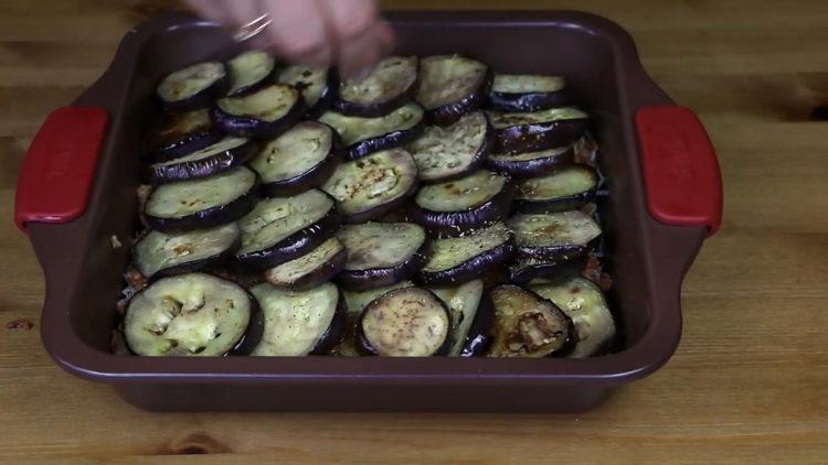 Metti le melanzane sulla carne macinata per preparare il pasto.