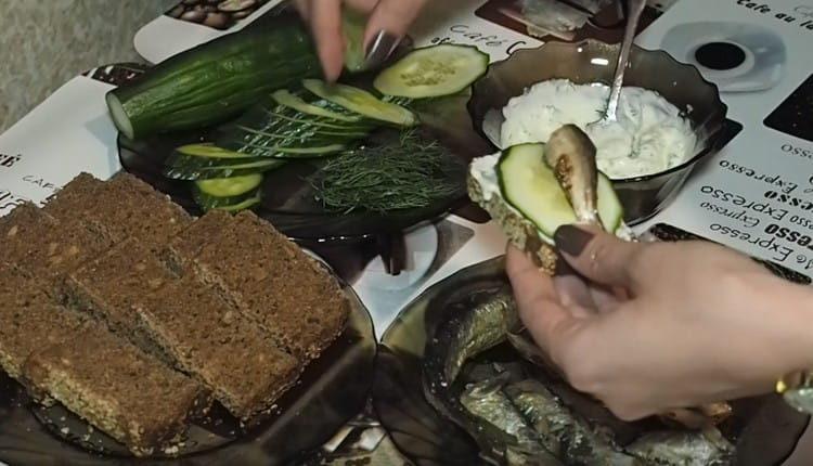 Distribuire una fetta di pane con la salsa, mettere un cerchio di cetriolo e spratto.