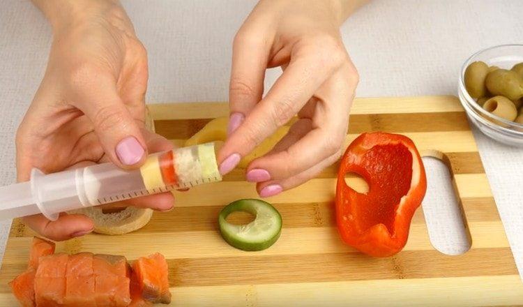 Strizzare i cerchi di pepe, pane e cetriolo con una siringa.