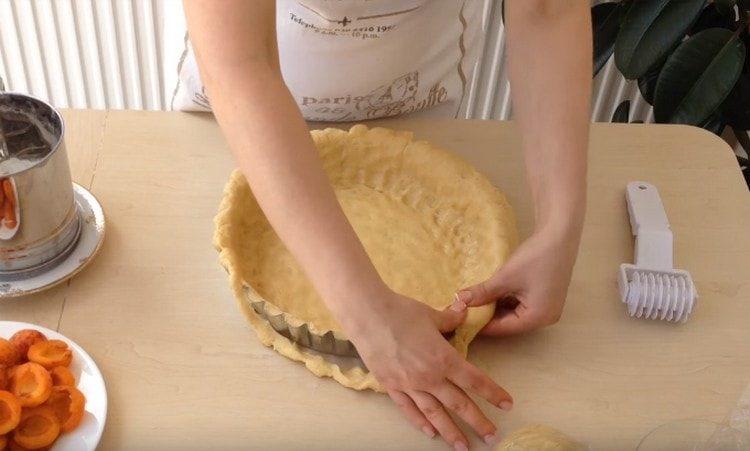 Dalla maggior parte dell'impasto formiamo il fondo e i lati della torta.