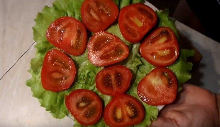 Tagliamo i pomodori a cerchi e spalmiamo sulle foglie di lattuga.