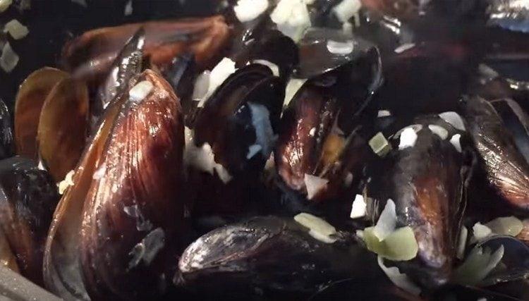 Mettiamo le cozze in una padella con la cipolla e l'aglio.