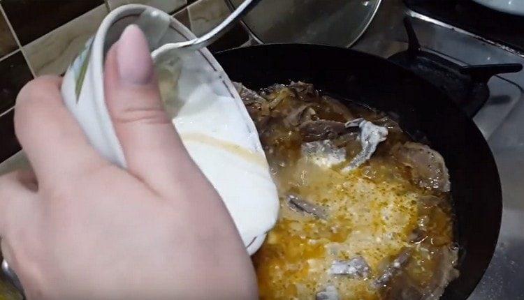 Versare il composto di panna acida nella padella, mescolare e cuocere a fuoco lento il piatto.