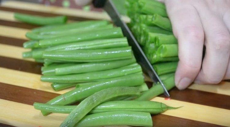 Tagliare i fagioli verdi a metà.