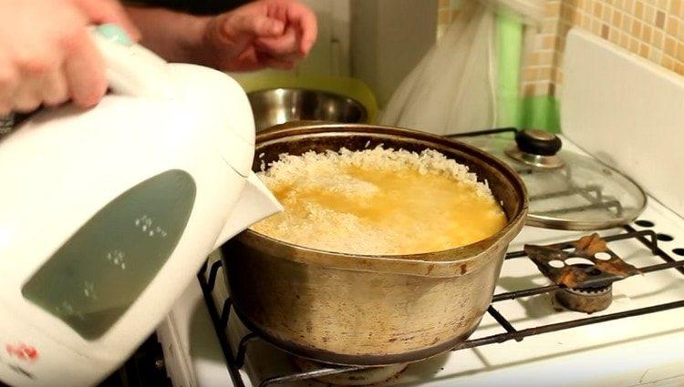 Distribuiamo il riso sulla carne con le verdure e aggiungiamo acqua.