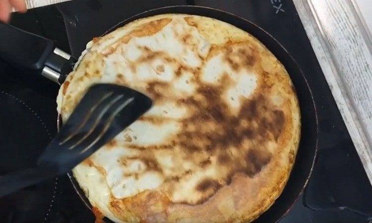 Girare delicatamente il pane pita con uova fritte sull'altro lato.